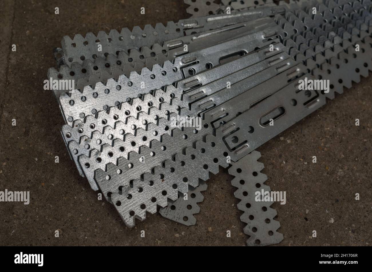 Gerader Aufhänger für Gipskarton. Trockenbauhalterungen. Lange Lochplatten sind aus verzinktem Stahl gefertigt. Vorrichtung für den Bau von Gipsplaste Stockfoto