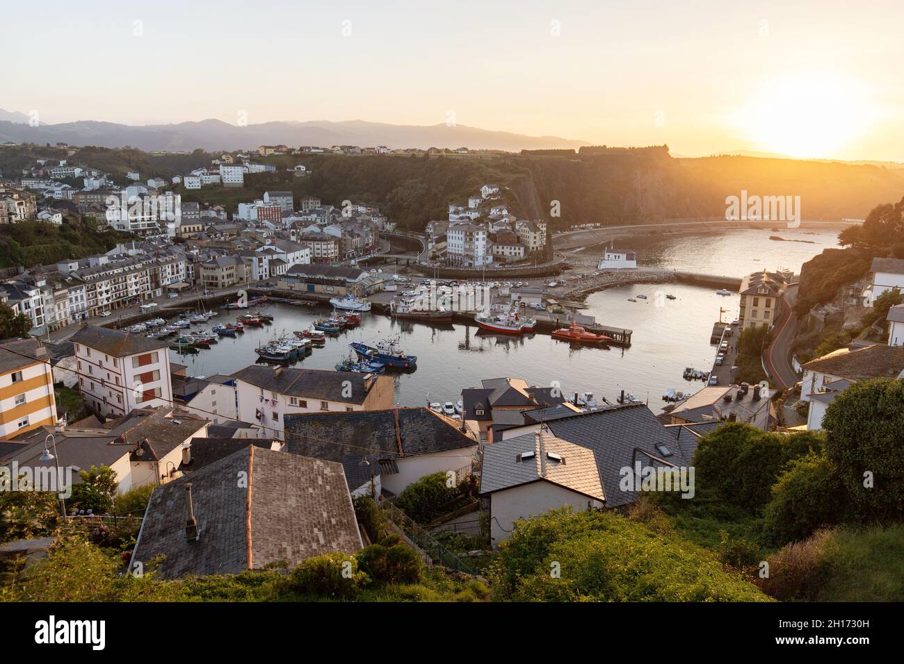 Von oben von Wohnhäusern in Küstengebiet auf grasbewachsenen Ufer in der Nähe von ruhigem Wasser mit verschiedenen Booten in Asturien entfernt Stockfoto