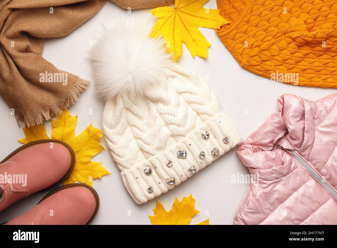 Ein Satz warmer Herbst-Winter-Kleidung mit gefallenen Ahornblättern auf weißem Hintergrund. Hutjacke Schal Stiefel Pullover. Flach liegend, Draufsicht Stockfoto