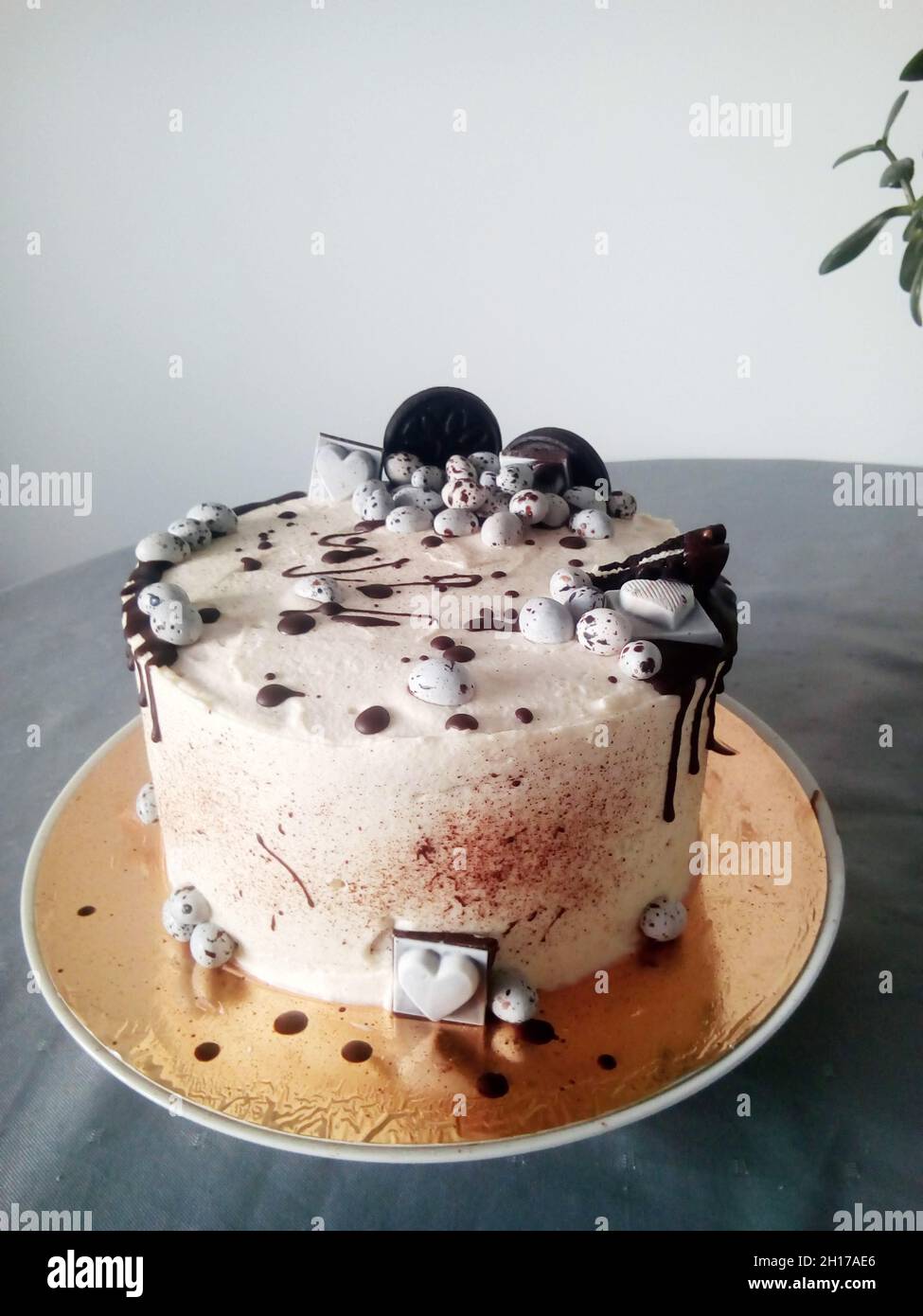 Schwarz-weißer Kuchen mit Keksen, Bonbons und Schokolade auf grauem Tisch Stockfoto