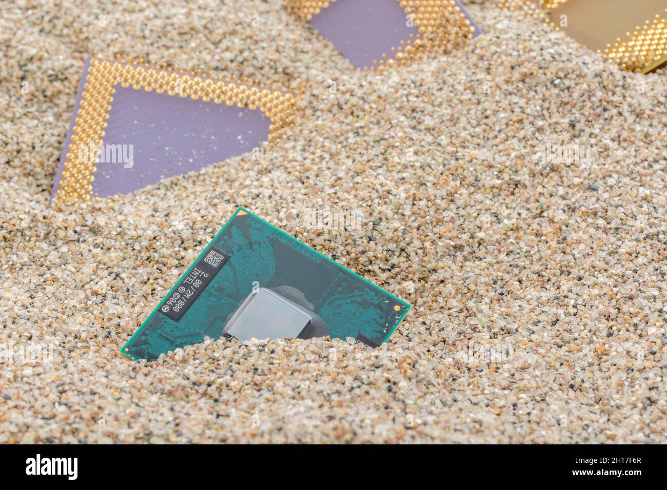 Uralte Computer-CPUs, die in einem Sandhaufen für Computer-Friedhof, Legacy-Computing begraben sind. Intel Merom, AMD Sempron, AMD Duron und K6 cpus vorhanden. Stockfoto