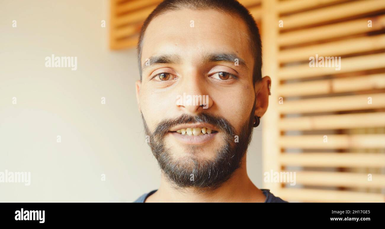 Ein indischer junger Mann, der drinnen steht und die Kamera anschaut Stockfoto