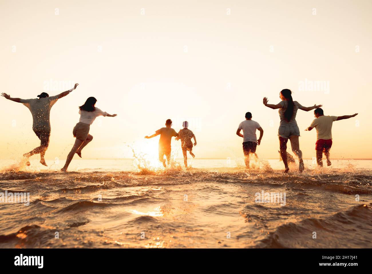 Eine große Gruppe junger Freunde oder eine große Familie haben Spaß und laufen am Sunset Beach. Konzept für Sommerferien Stockfoto