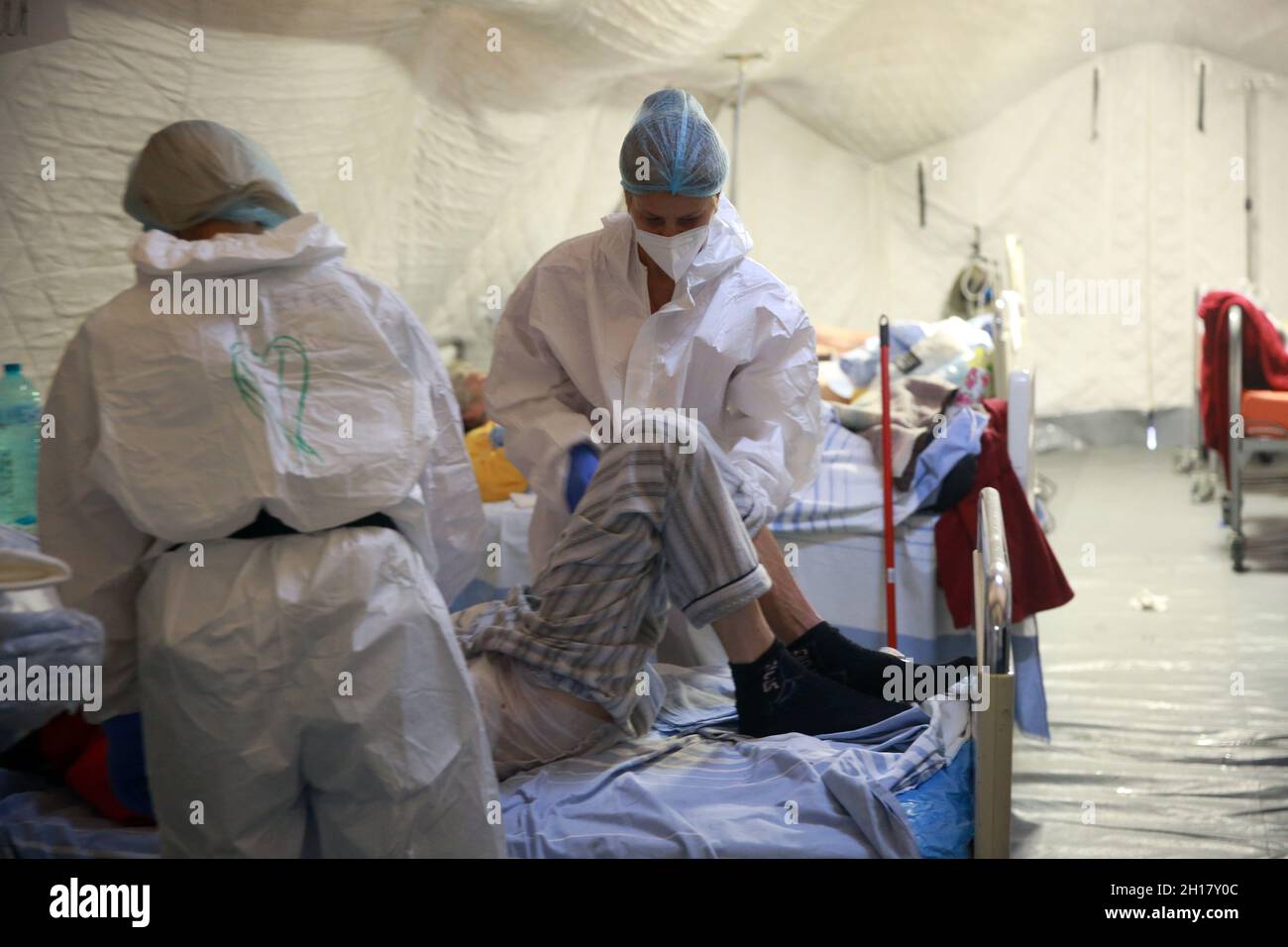 BUKAREST, RUMÄNIEN - 15. Oktober 2021: Medizinisches Personal, das persönliche Schutzausrüstung (PSA) trägt, kümmert sich in einem Zelt um die Patienten, eine Verlängerung der Th Stockfoto