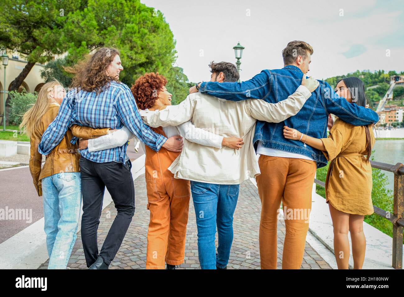 Eine Gruppe von glücklichen Teenagern, die die Straße entlang gehen und sich unterhalten - Studenten, die zusammen gehen und Spaß haben - Tourismus, Reisen und lei Stockfoto