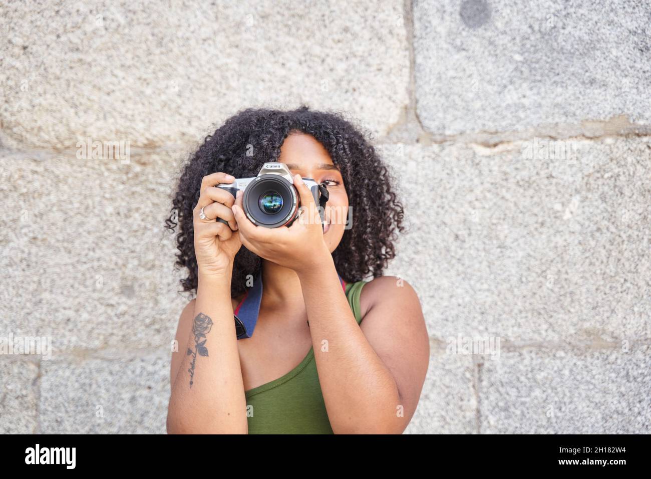 Junge Latina mit lockigen Haaren Fotografieren mit DSLR-Kamera mit Platz für Text Stockfoto