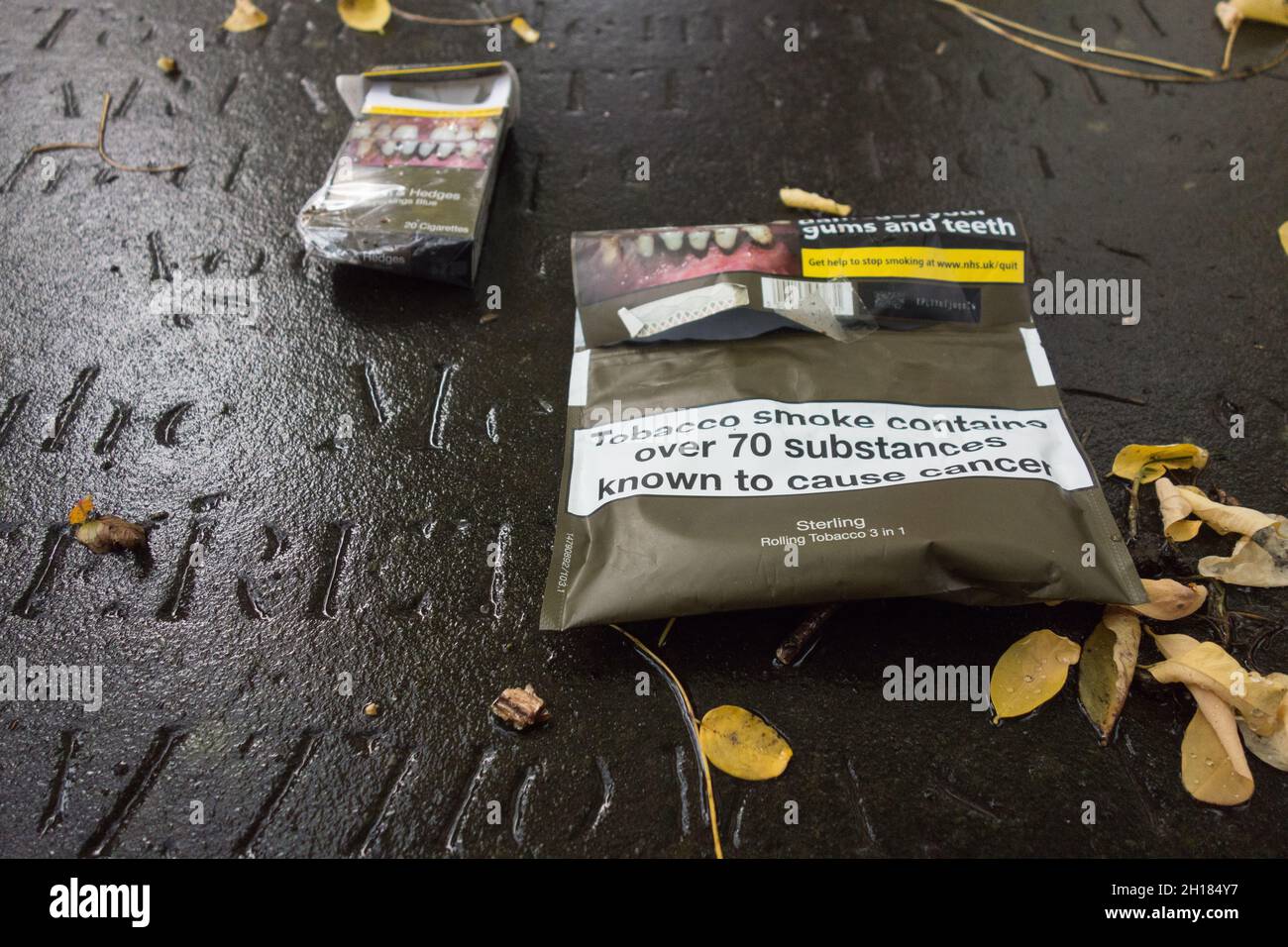 Grafische Gesundheitswarnung auf rollenden Tabakverpackungen, die auf einem alten Grab auf einem Friedhof in London ruhen Stockfoto