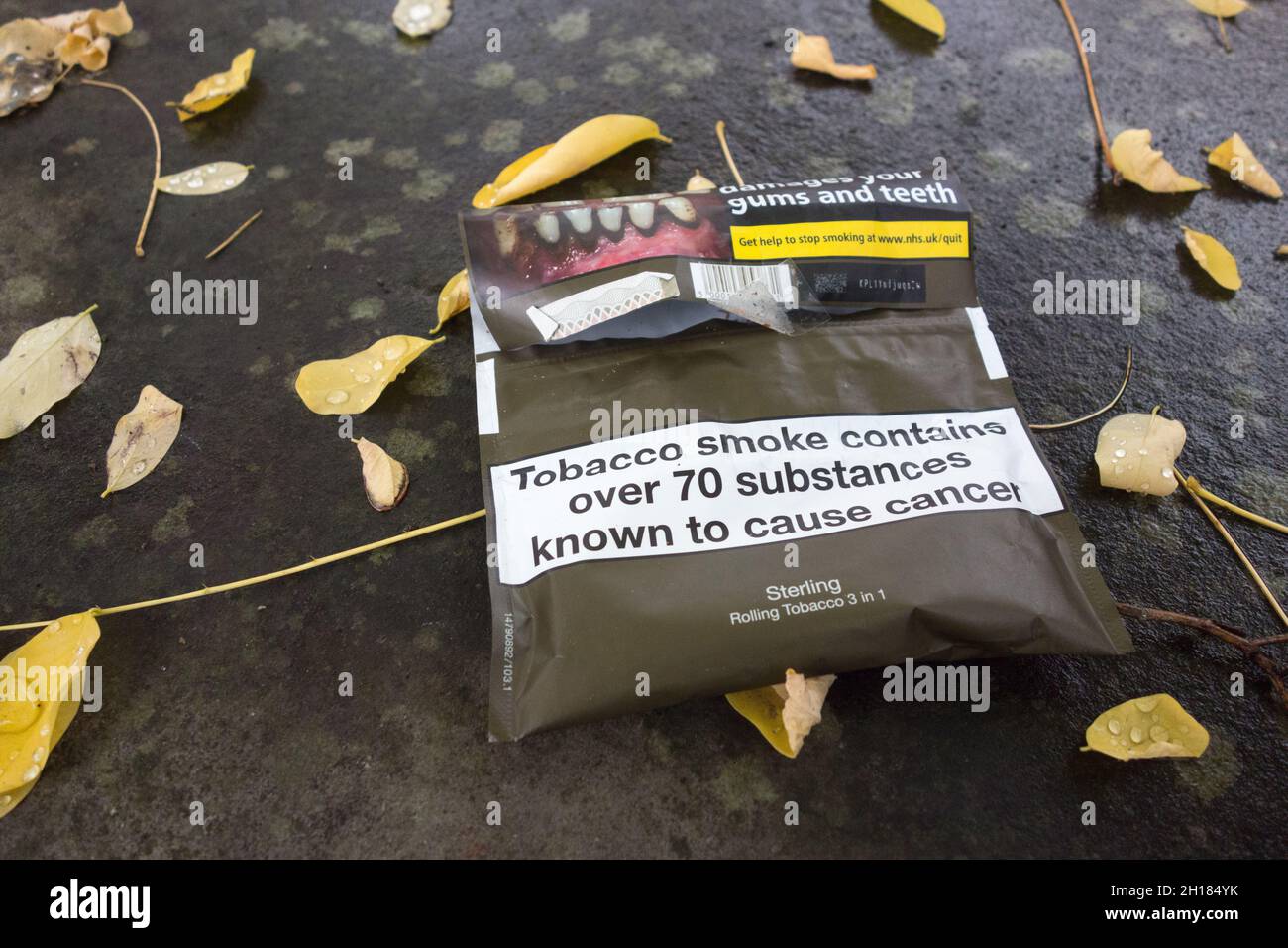 Grafische Gesundheitswarnung auf rollenden Tabakverpackungen, die auf einem alten Grab auf einem Friedhof in London ruhen Stockfoto