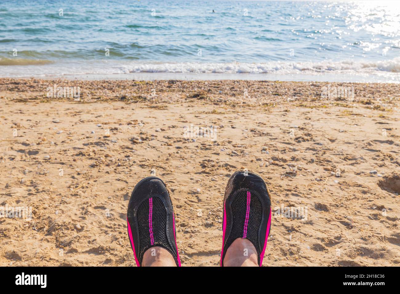 Сlose Blick auf Badeschuhe auf den Füßen eines Mannes vor dem Hintergrund des weißen Sandstrandes Meer. Griechenland. Stockfoto