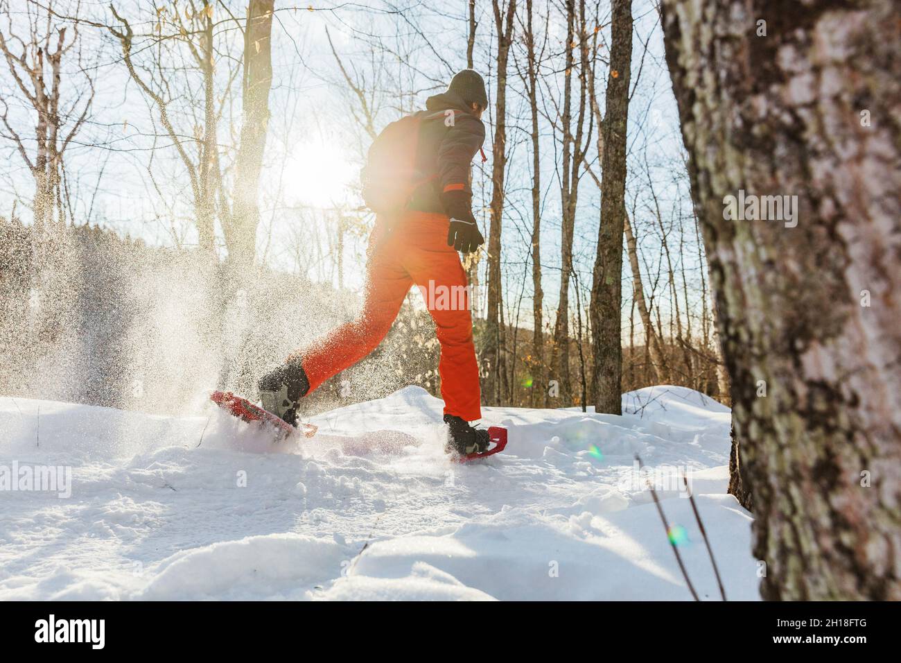 Schneeschuhwandern Outdoor Winter Fitness Aktivität glücklicher Mann läuft in Schneeschuhen im Schnee von hinten in sonniger Waldlandschaft Stockfoto