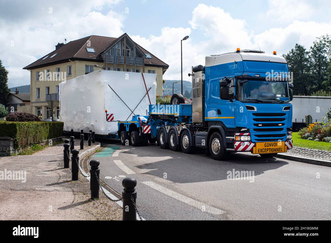 Ein LKW mit außergewöhnlicher Ladung durchquert eine kleine Stadt auf einer schmalen Straße Stockfoto