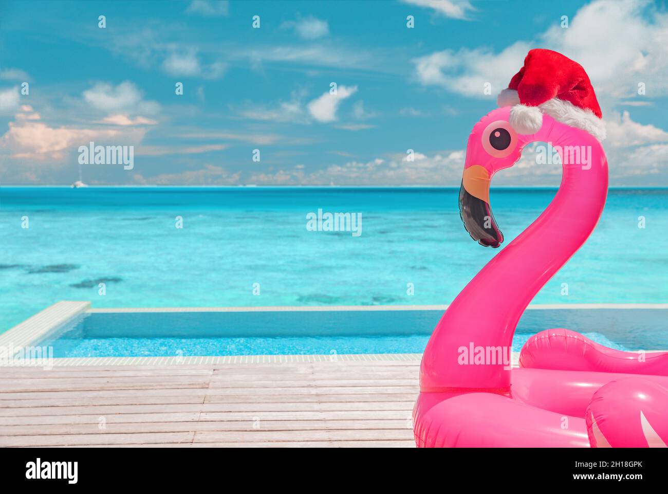 Weihnachten Strand Sommerurlaub Flamingo Pool Schwimmer mit weihnachtsmütze Reise Hintergrund für Winterferien Stockfoto