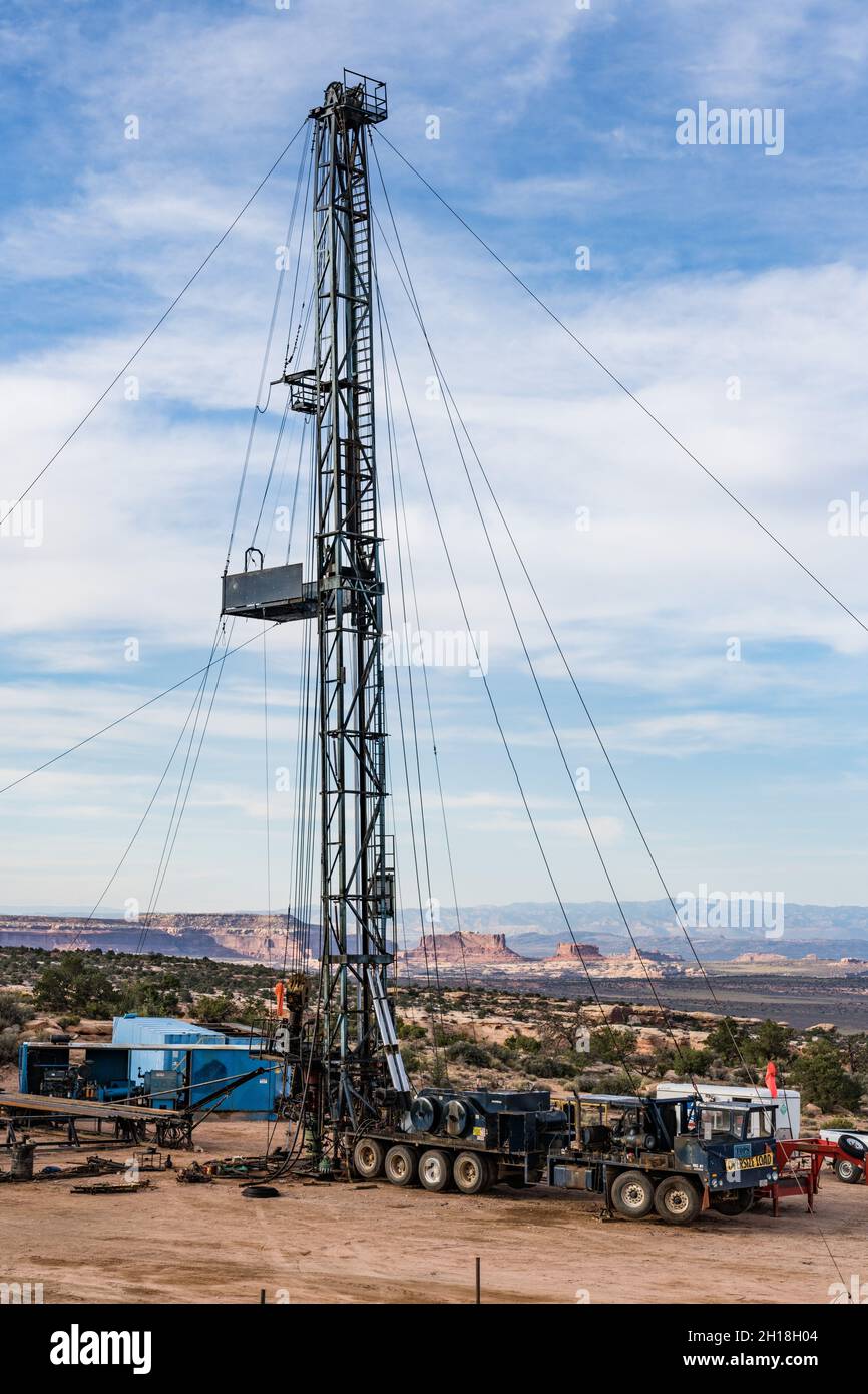 Eine Zieheinheit oder ein Überarbeitungs-Rig an einer Ölbohrstelle in Utah. Dahinter stehen die Monitor & Merrimac Buttes & Book Cliffs. Stockfoto