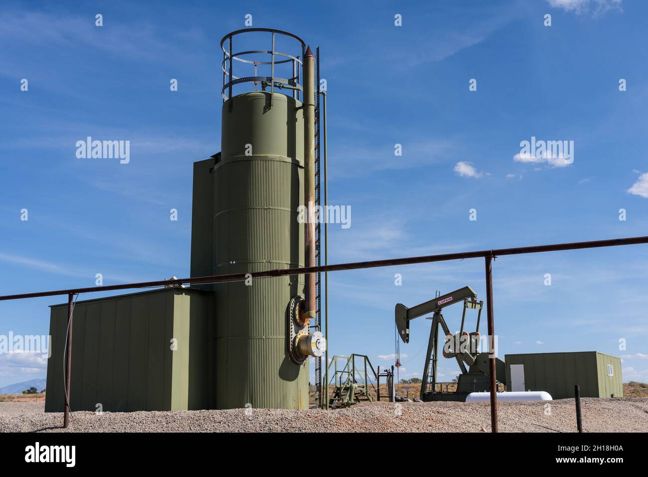 Eine konventionelle Hydraulikpumpe mit Pferdekopf und ein Heiztreater an einem Ölbohlstandort in Utah. Stockfoto