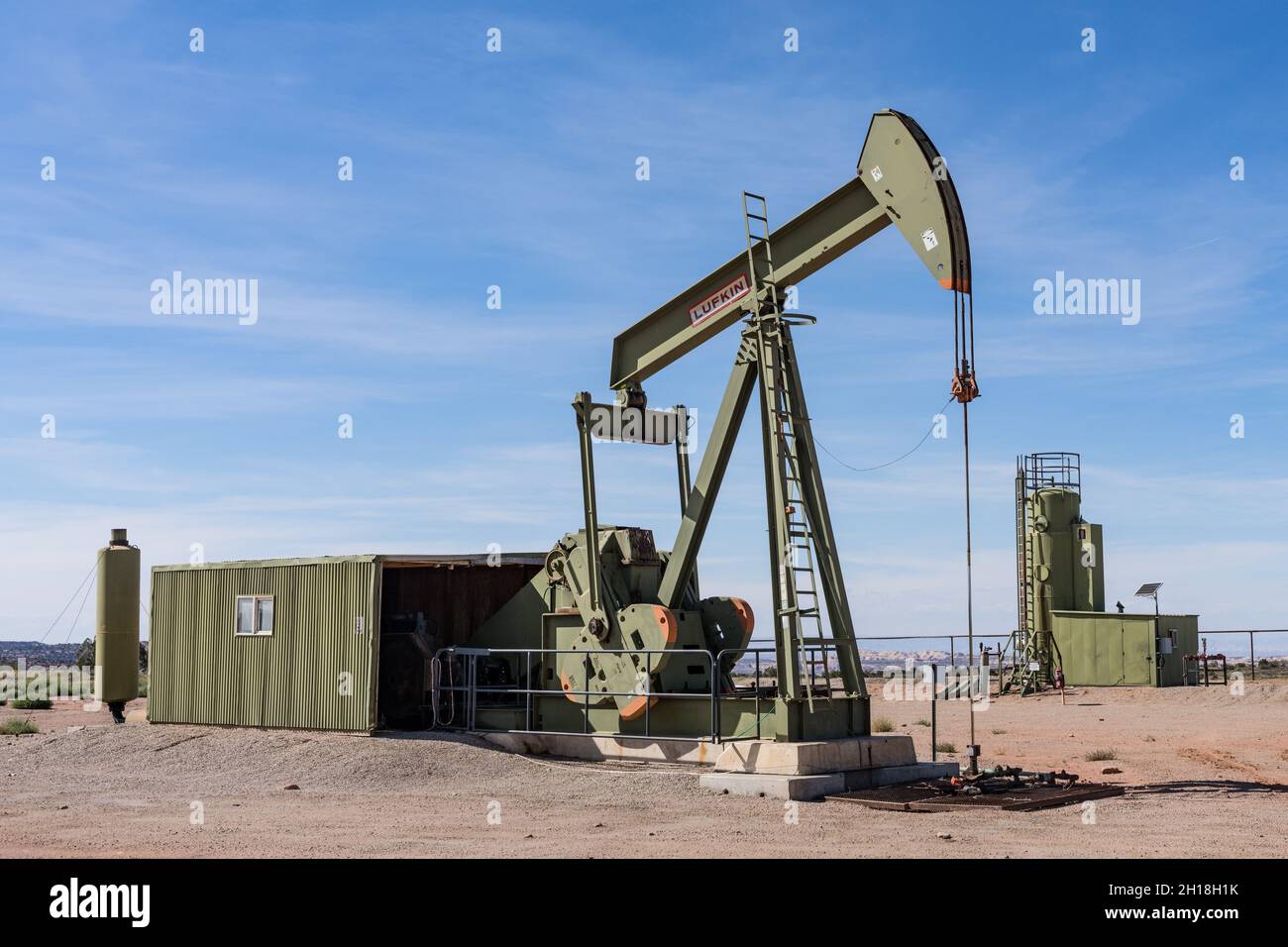 Eine konventionelle Hydraulikpumpe mit Pferdekopf und ein Heiztreater an einem Ölbohlstandort in Utah. Stockfoto