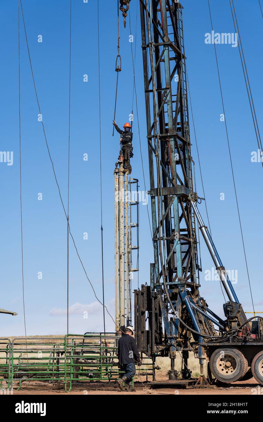 Ein Brunnendienst auf einer hydraulischen Pumpeinheit bereitet sich darauf vor, den fahrenden Block an der Einheit zu befestigen. Stockfoto