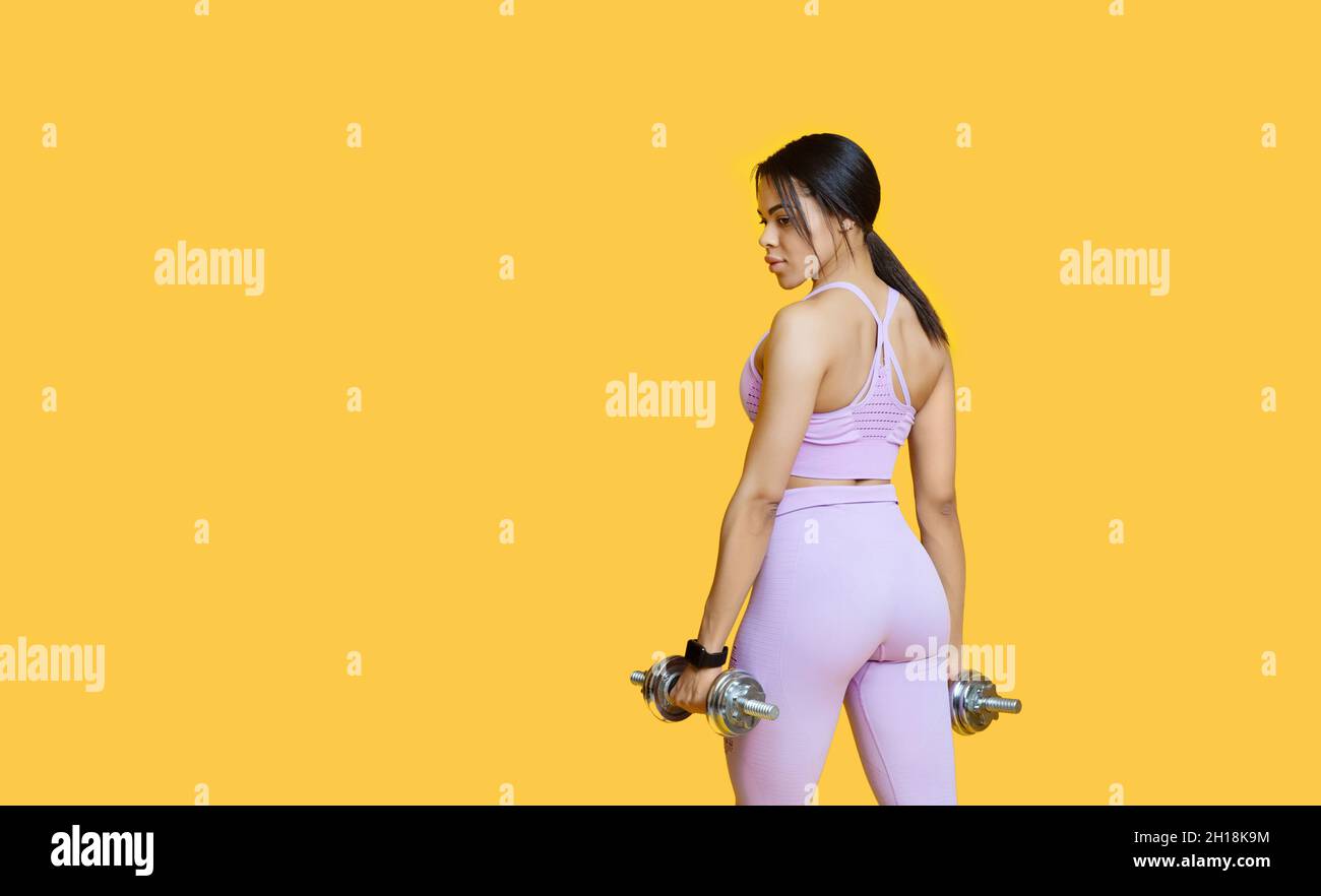 Fitnessmodell. afroamerikanische Dame, die mit Hanteln trainiert, auf gelbem Hintergrund posiert, Panorama mit Kopierraum Stockfoto