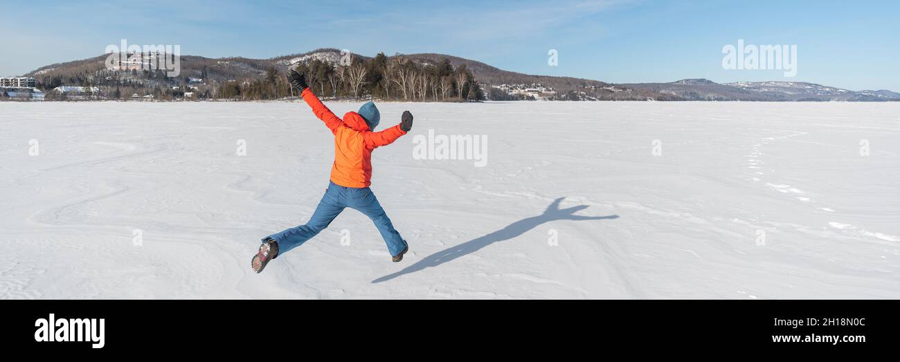 Winterspaß glückliche Menschen springen vor Freude auf gefrorenem weißen Schnee, Naturlandschaft Banner, Kanada. Warme Oberbekleidung und Accessoires für Outdoor-Aktivitäten Stockfoto