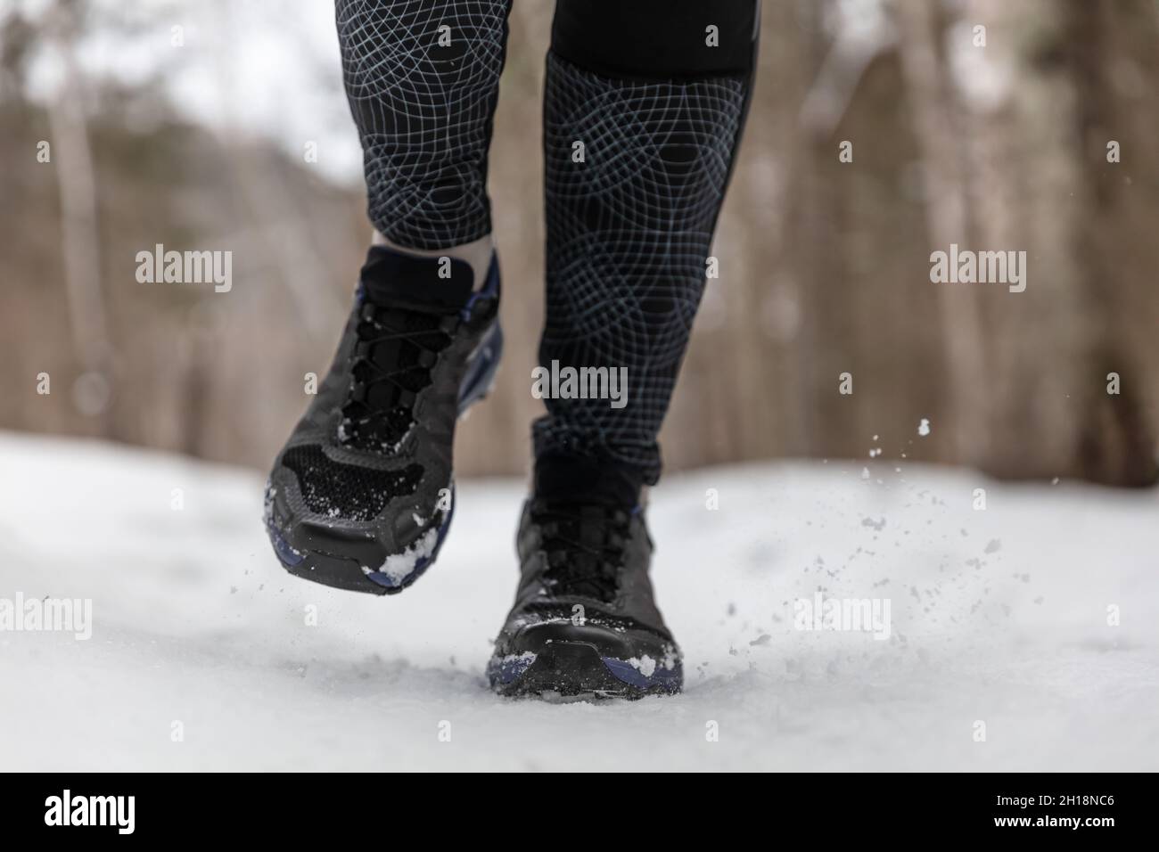 Winterlaufschuhe Frau trainiert im Freien Kardio beim Joggen auf weißem Schnee bei kaltem Wetter. Nahaufnahme der Füße mit Fitnessschuhen Stockfoto
