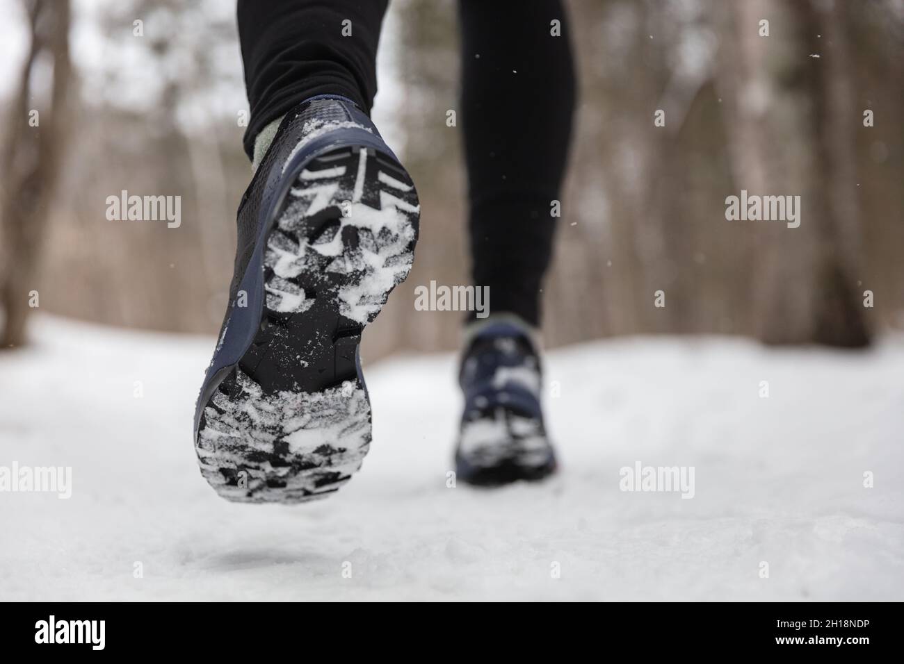 Wintersport Fitness Lifestyle Sportler laufen mit Laufschuhen auf Schnee und rutschigem Eis und benötigen Traktionsohlen auf vereisten Gehwegen. Rauf nach draußen Stockfoto