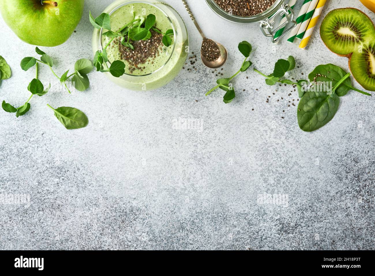 Zutaten für grünen Smoothie, frische Bio-Spinaterde Microgreens, Banane, Kiwi, Apfel- und Chiasamen auf hellgrauem Betongrund. Gesund Stockfoto