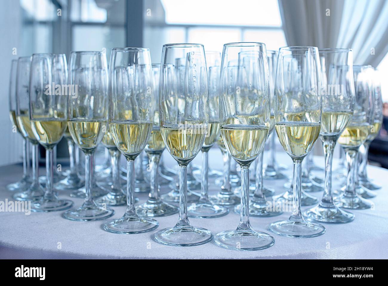 Champagner oder Sekt in langen Gläsern auf einem weißen Tisch, einem typischen Getränk, das zur Feier von Hochzeiten oder Geburtstagsfeiern verwendet wird Stockfoto