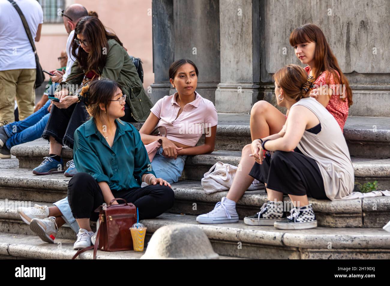 Junge Frauen oder Jugendliche sitzen auf den Stufen der Fontana di S. Maria in Trastevere in Rom, Italien Stockfoto