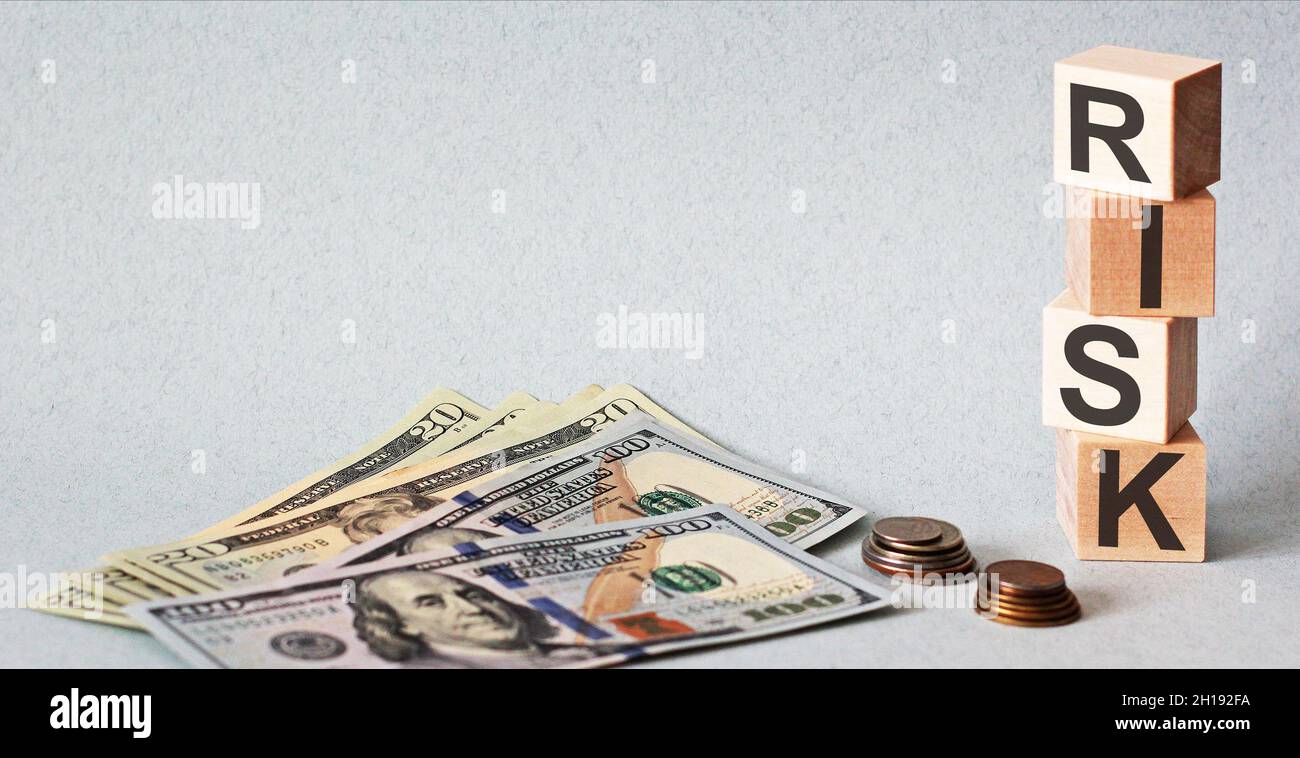 Text auf Holzwürfeln Risiko und Geld mit Münzen auf blauem Hintergrund Stockfoto