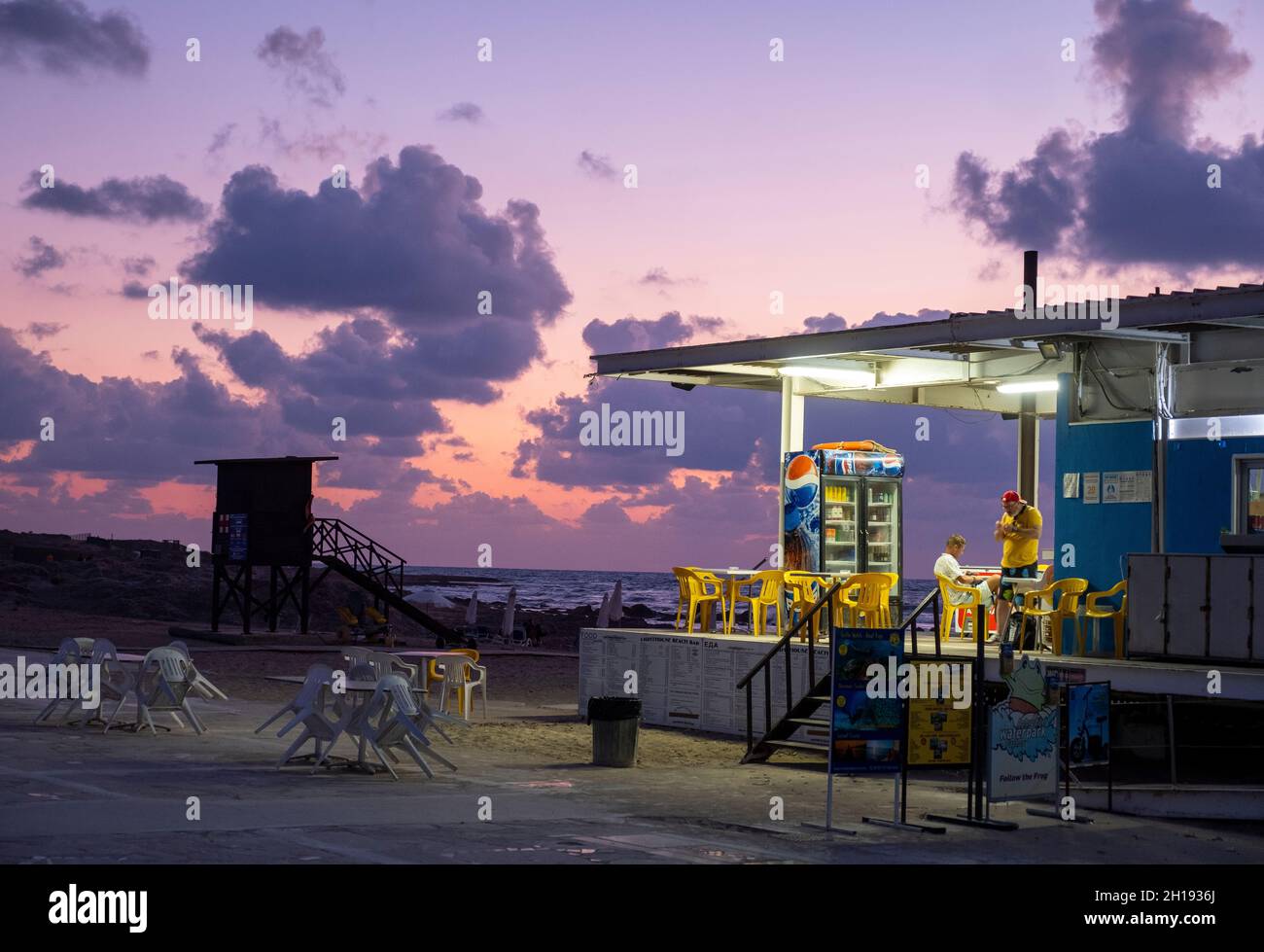 Strandcafe am Leuchtturm von Paphos in der Abenddämmerung, Paphos, Zypern. Stockfoto