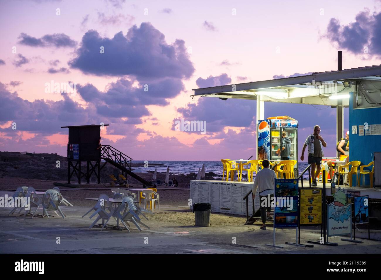 Strandcafe am Leuchtturm von Paphos in der Abenddämmerung, Paphos, Zypern. Stockfoto
