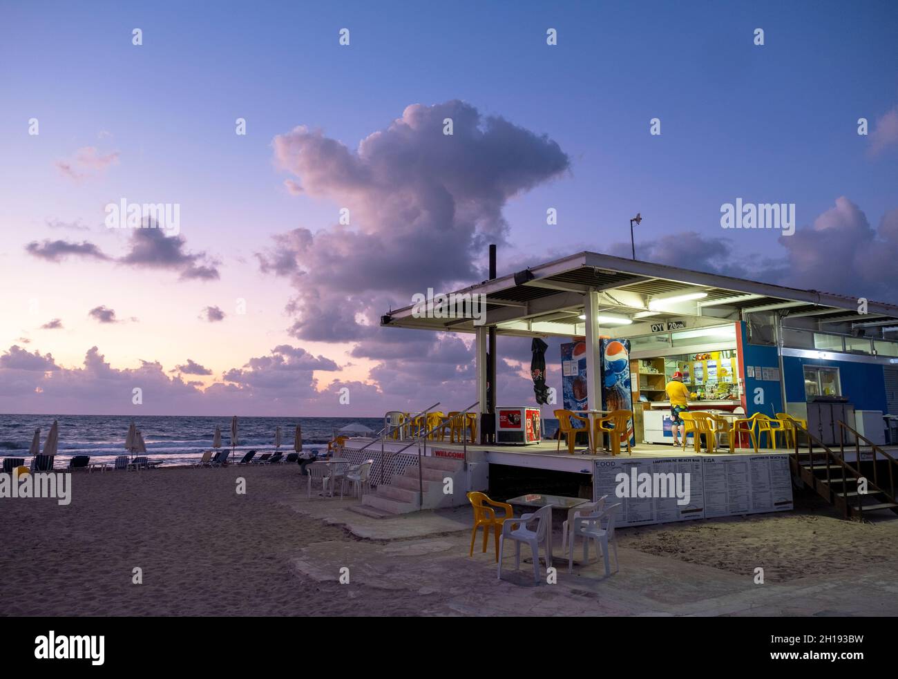 Strandcafe am Leuchtturm von Paphos in der Abenddämmerung, Paphos, Zypern. Stockfoto