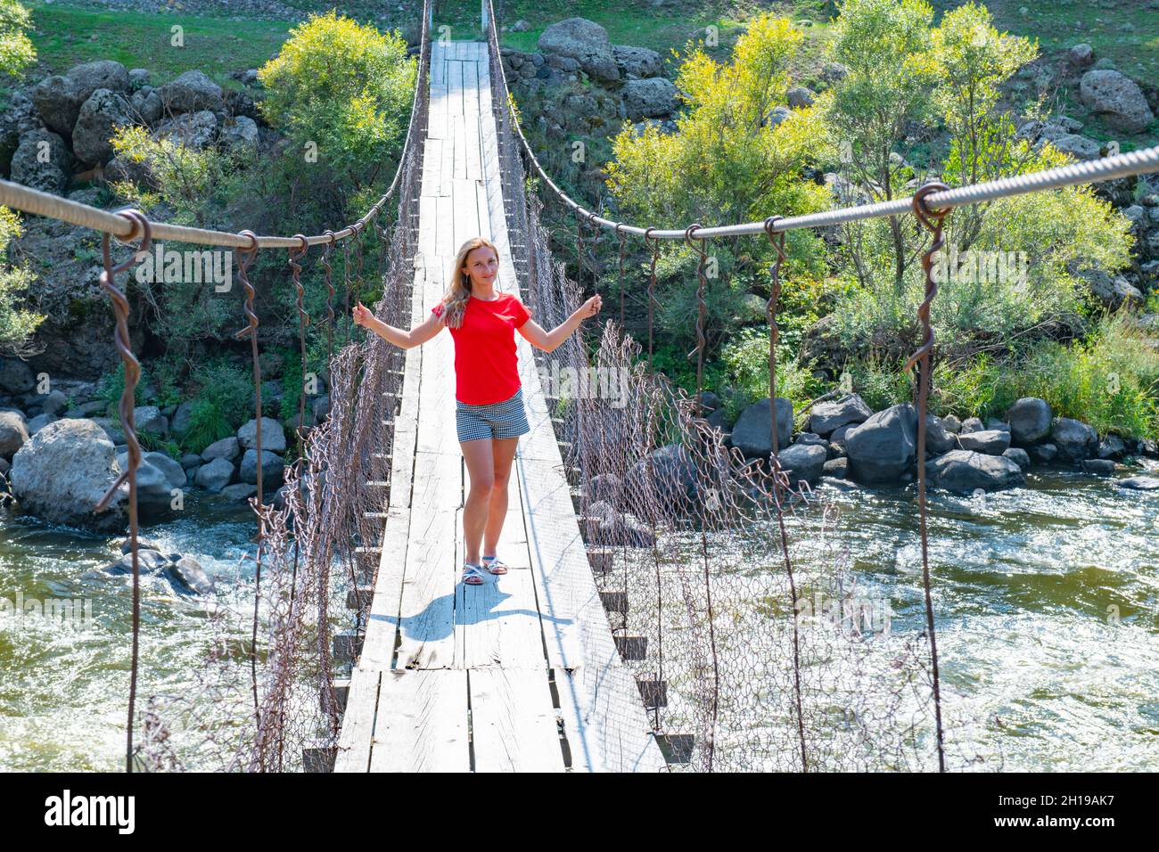 Ein Mädchen in Rot steht auf der Unterweltbrücke in georgien Stockfoto