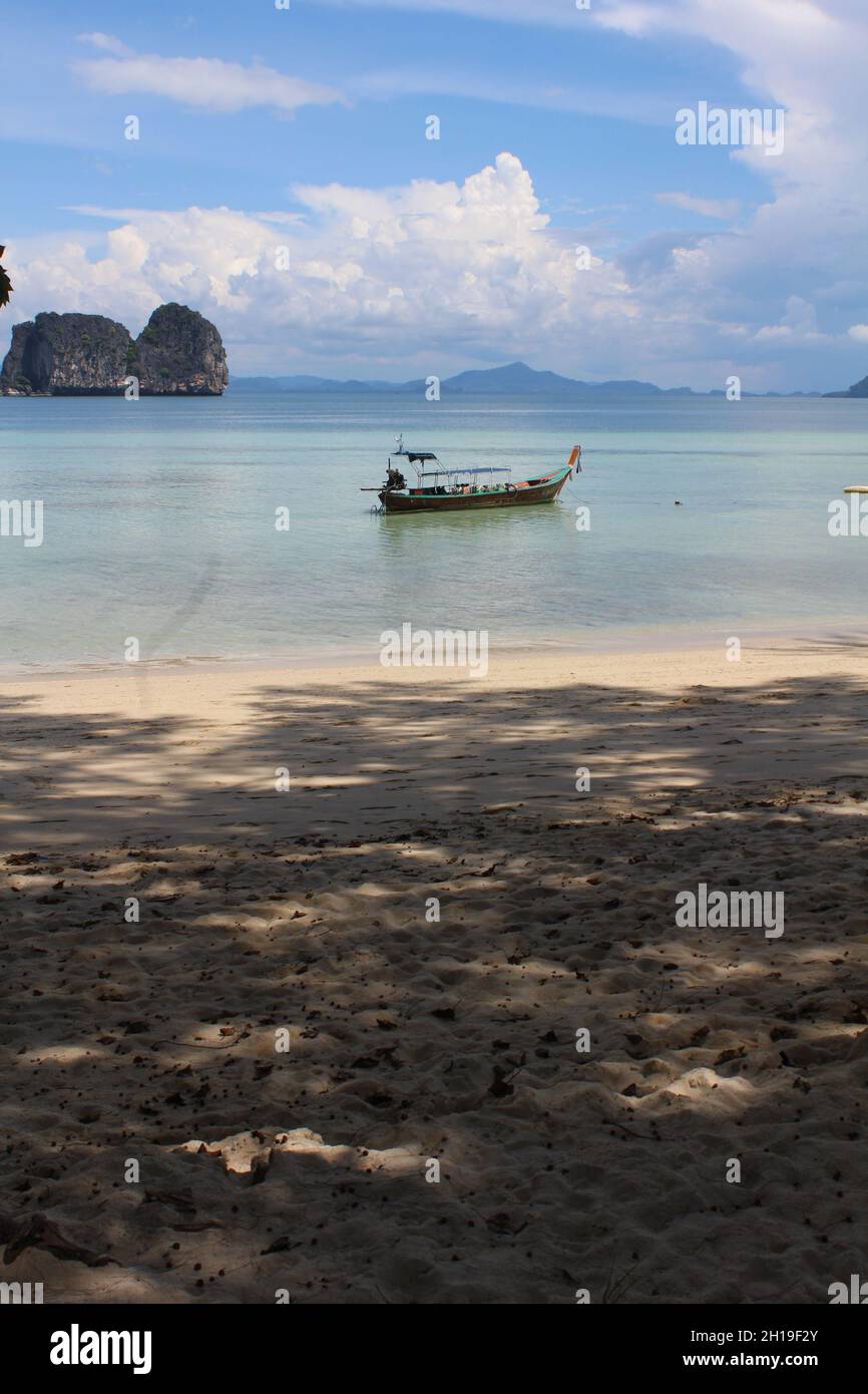 Das alte Boot mit einem Hintergrund der Insel Ko Ngai über dem Meerwasser vor einem bewölkten Himmel in Thailand Stockfoto