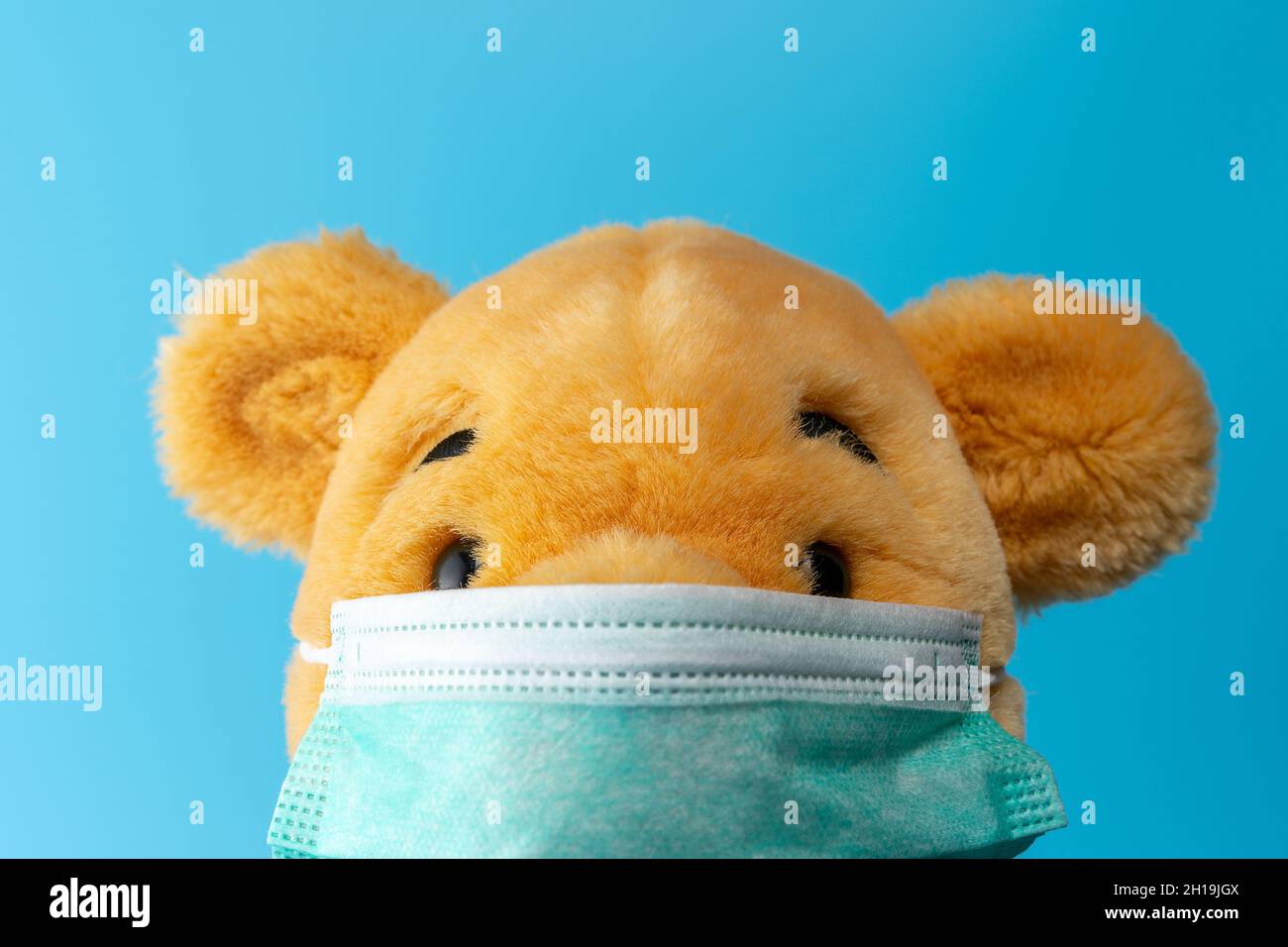 Kreative Komposition mit Gelbbär mit Virusmaske. Minimaler Ausbruch des Corona-Virus. Urlaubskonzept. Stockfoto