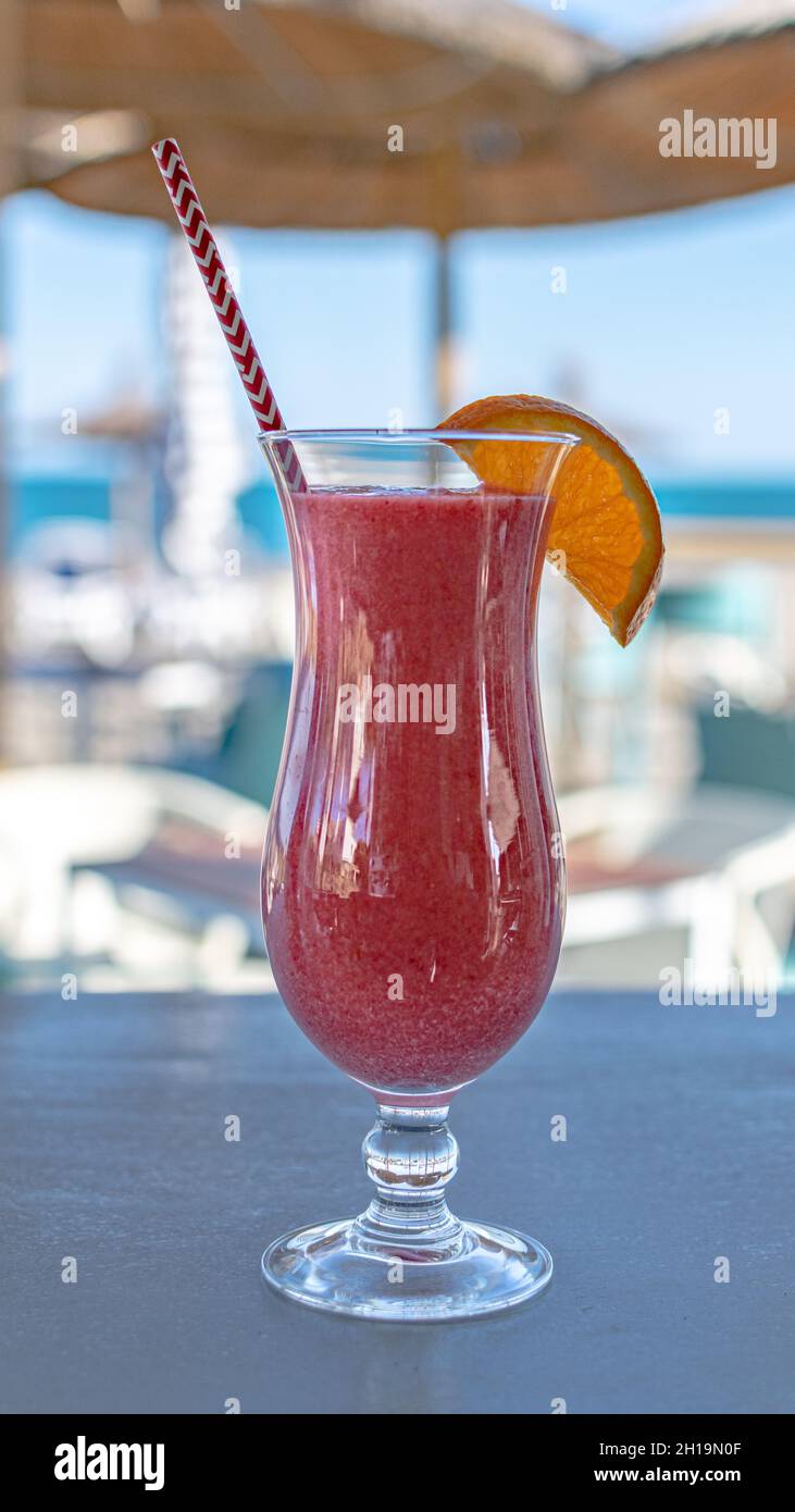Nahaufnahme eines frisch zubereiteten tropischen Smoothie-Cocktails mit roten Früchten und Hintergrund am Strand Stockfoto
