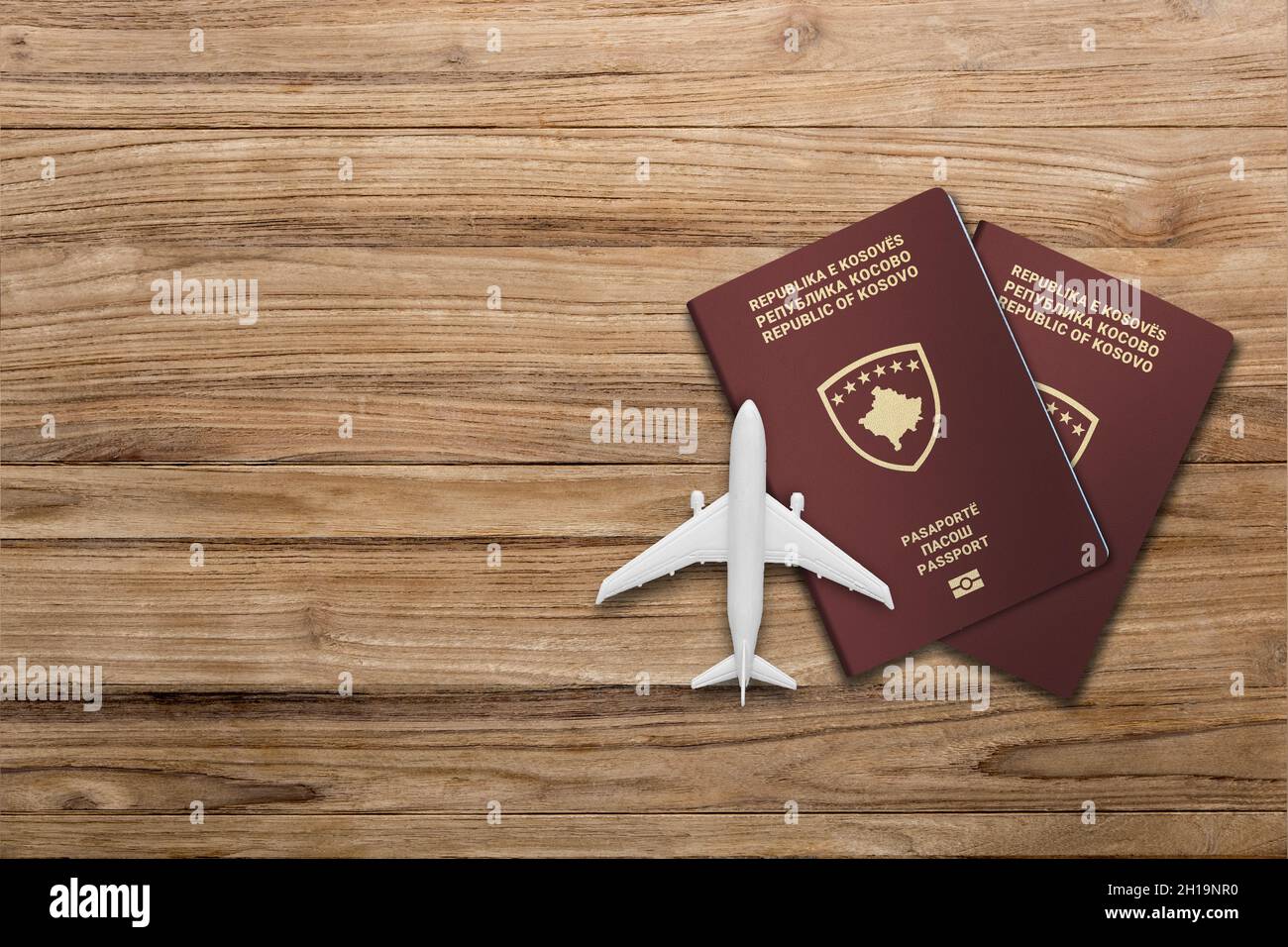 Flugzeugmodell und kosovarische Pass auf Holzhintergrund, flach liegend. Platz für Text Stockfoto