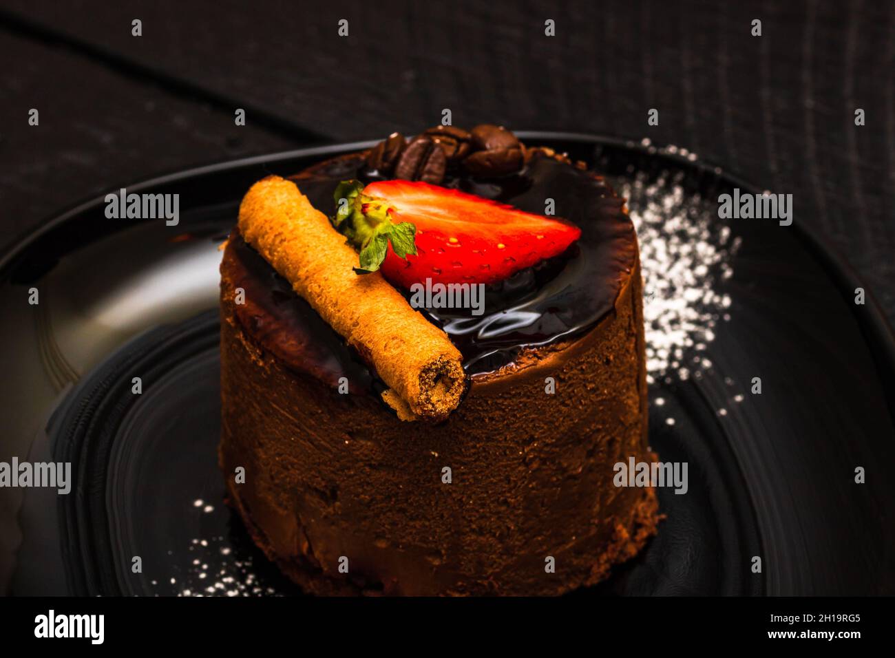 Nahaufnahme eines Schokoladenmousse-Desserttisches mit Erdbeere und Schokoladenstift auf einer schwarzen Platte; Kochkonzept Stockfoto