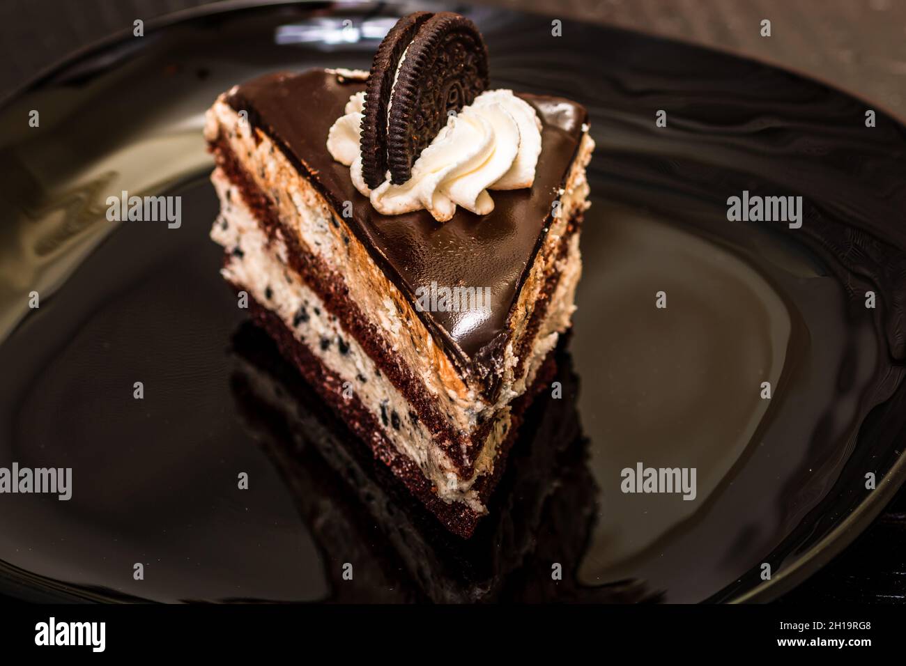 Eine Nahaufnahme eines Schokoladenmousse-Dessertkuchens mit einem Oeo auf einer schwarzen Platte; Kochkonzept Stockfoto