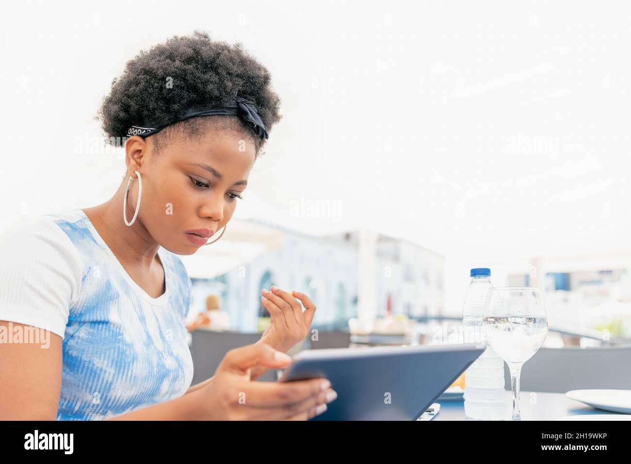 Eine seriöse Erwachsene Frau, die auf einem Restaurant im Freien sitzt und ihr digitales Tablet benutzt und anschaut Stockfoto