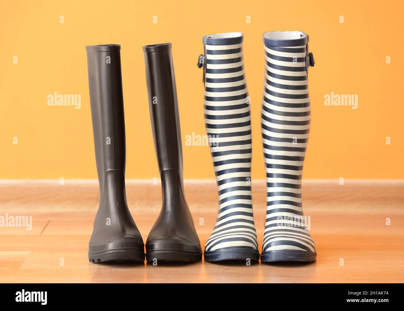 Zwei Paar Gummistiefel auf dem Boden vor farbigem Hintergrund Stockfoto