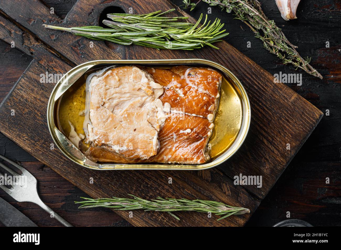 Wild Alaska Lachs Räucherfischset aus der Dose, auf Holzschneidebrett, auf altem dunklen Holztisch Hintergrund mit Kräutern und Zutaten, Draufsicht flaches Lay Stockfoto