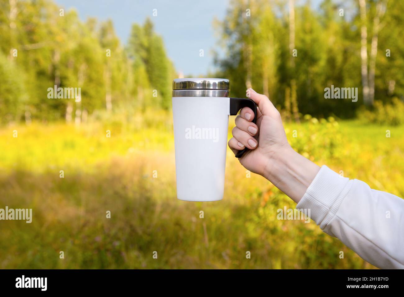 Nachbau eines weißen Reisekrug an einer Birke. Leerer Becher als Design-Promotion. Stockfoto