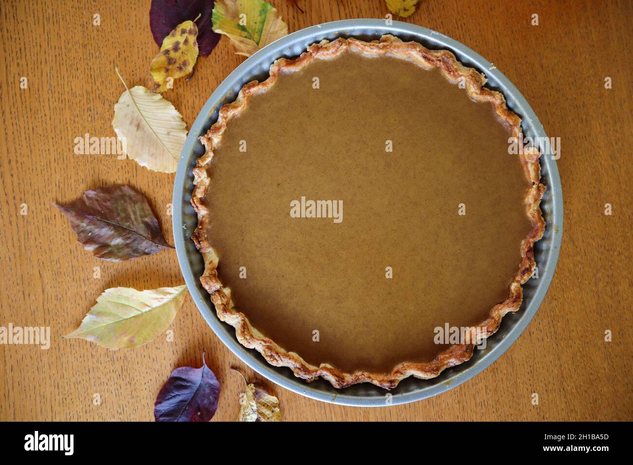 Top-Down von Kürbiskuchen mit Zimt und Blättern auf Holztisch. Leckere Hausgemachte Festliche Süße Speisen. Stockfoto