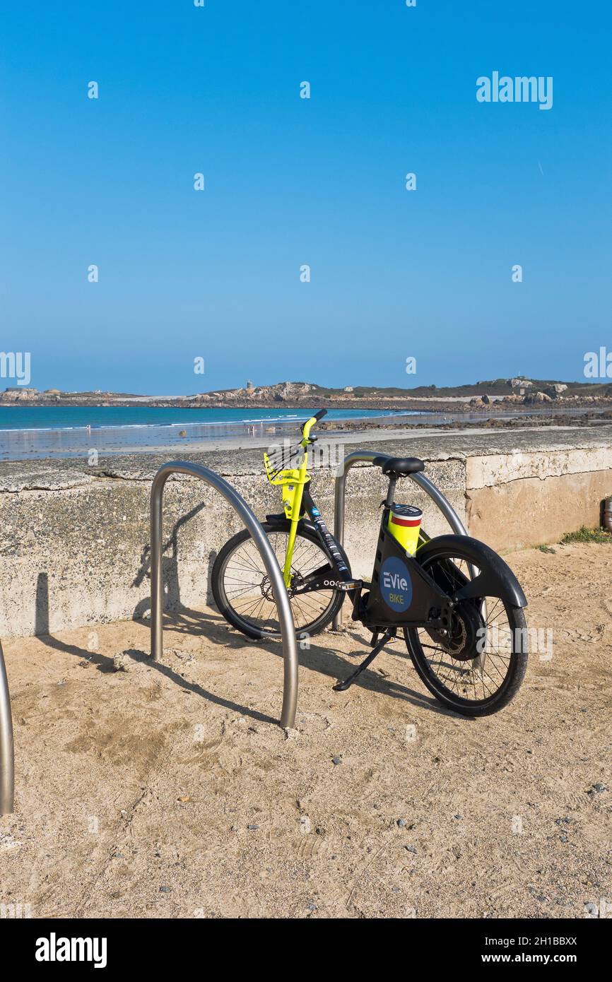 dh Evie Bike EBIKE GUERNSEY Elektrofahrräder stehen am Strand geparkt Stockfoto
