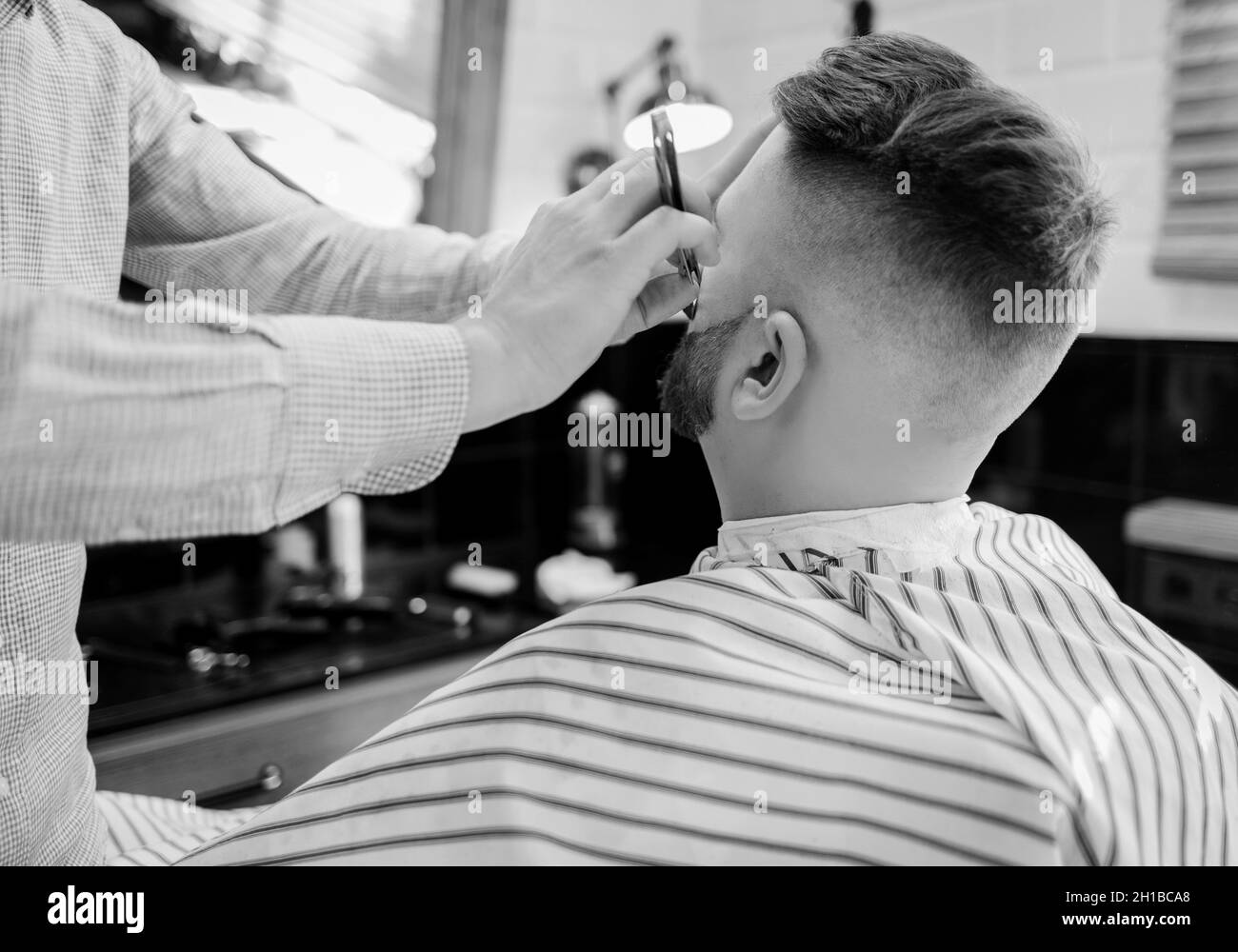 Barber arbeitet mit einem Rasiermesser mit einem Kunden. Ein bärtiger Mann rasiert in einem Friseursalon Stockfoto