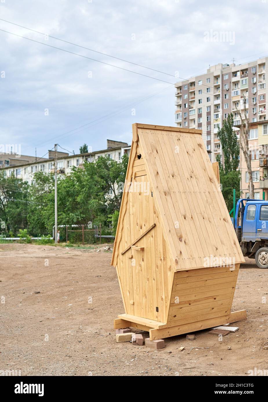 Mitten in einer Stadtstraße steht eine Holztoilette Stockfoto