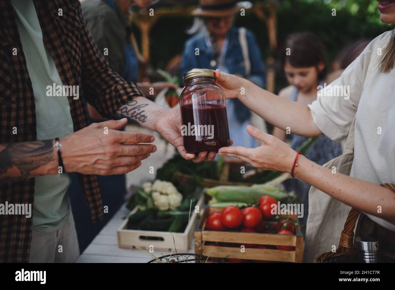 Nahaufnahme einer Frau, die auf dem lokalen Bauernmarkt im Freien Bio-Saft kauft. Stockfoto