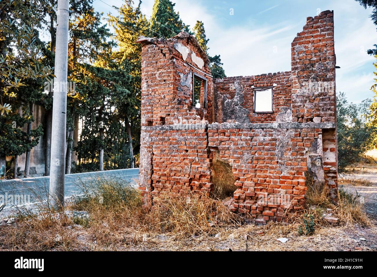 Ruinen eines verlassenen zweistöckigen Backsteinhauses, das sich außerhalb eines ländlichen Wiesenfeldes befindet. Stockfoto