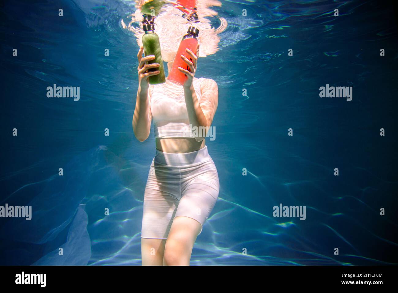 Fitness-Mädchen mit bunten Smoothie. Frische unter Wasser, schwimmt und taucht. Stockfoto