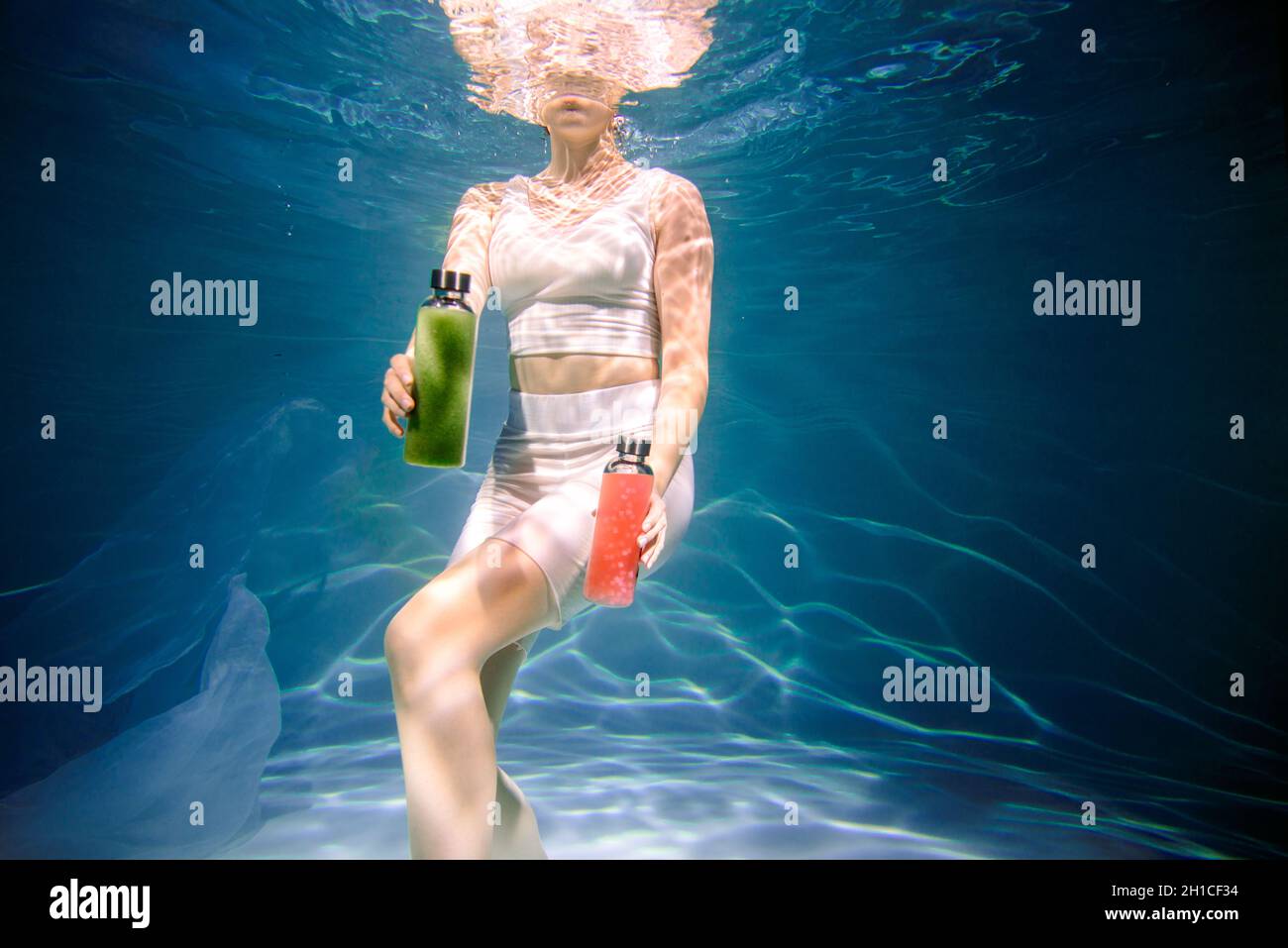 Fitness-Mädchen mit bunten Smoothie. Frische unter Wasser, schwimmt und taucht. Stockfoto